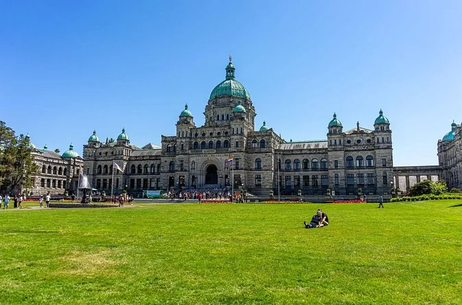 Die Parliament Buildings mit Kuppel hinter einem weiten grünen Rasen an einem sonnigen Tag